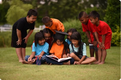 Youth counselor engaging with children reading outdoors at a Cops 'n Kids program