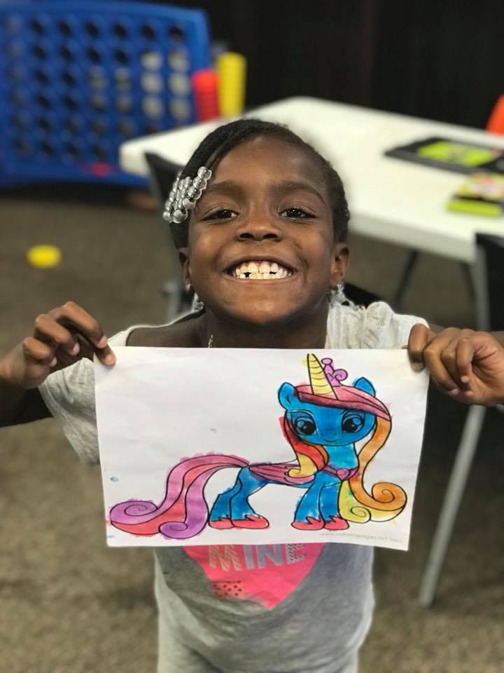Child proudly showing artwork they created at a Cops 'n Kids program
