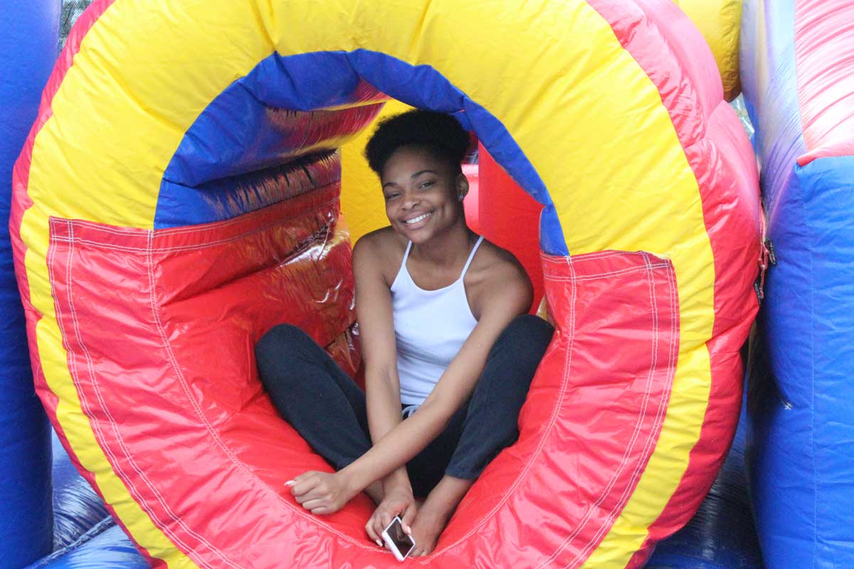 Young participant sitting inside a colorful bounce house at a Cops 'n Kids event