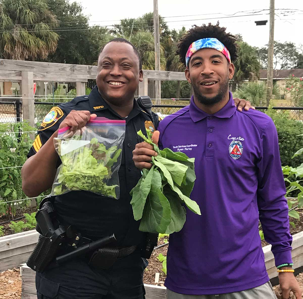Cops 'n Kids staff member in a purple shirt holding freshly harvested leafy greens